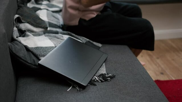 Cropped view of a man putting on headphones scrolling social media on laptop at home