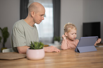 Obraz na płótnie Canvas People with cochlear implant system. Kid study to hear with her father, learning with video on tablet. Installation cochlear implant on child girl ear for restores hearing.
