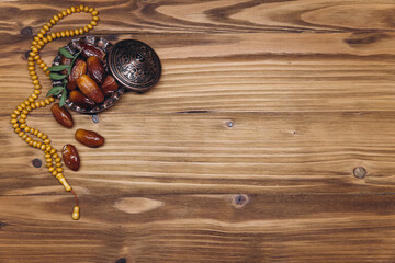 Table top view image of decoration Ramadan Kareem, dates fruit and rosary beads on wooden background. Flat lay with copy space.