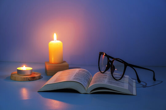 Christian Holy Bible with candles lighting on blue background