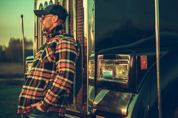 Trucker Resting in Front of His Semi Truck Grille