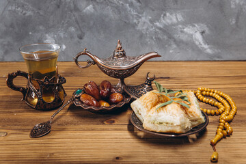 Ramadan concept, cup of tea, plate of sweet dates and baklava, copy space