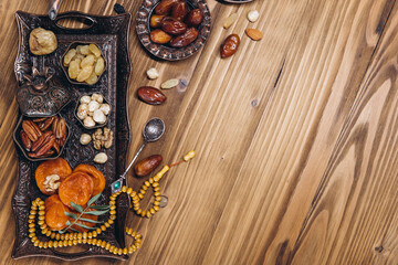 Dried dates and tea on a wooden table. Arabic traditional dishes, pots and dates fruits. Ramadan Kareem, Eid mubarak concept. Top view. Flat lay. Copy space