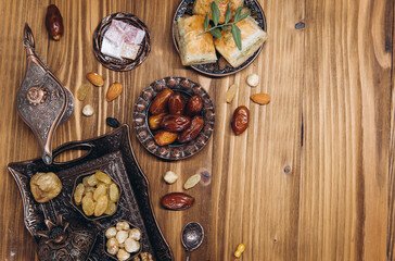 Dried dates and tea on a wooden table. Arabic traditional dishes, pots and dates fruits. Ramadan Kareem, Eid mubarak concept. Top view. Flat lay. Copy space