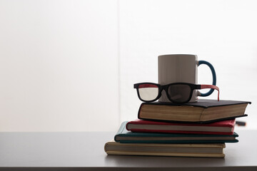 Stack of colorful books, open book and cup on wooden table. Back to school. Copy space