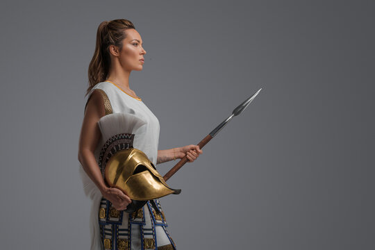 Portrait of isolated on grey background female greek warrior with spear.