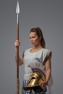 Portrait of isolated on grey background female greek soldier with spear.