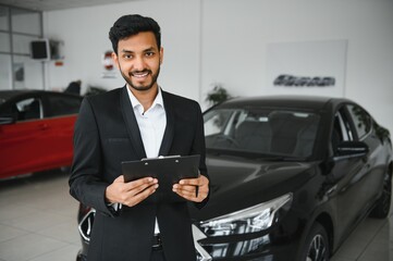 Fototapeta na wymiar indian cheerful car salesman at showroom.
