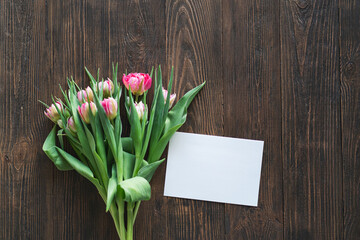 Stylish greeting card. Fresh tulips flat lay on wood background. Floral Greeting card template with space for text. Happy women's day. Happy Mother's day. Stylish greeting card