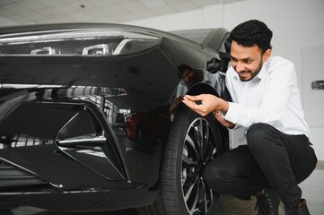 Fototapeta premium A young Indian man chooses a new car at a car dealership
