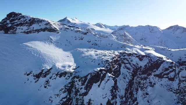 Aerial drone footage of sideways flight over scenic snowy mountain range in winter in the European Alps
