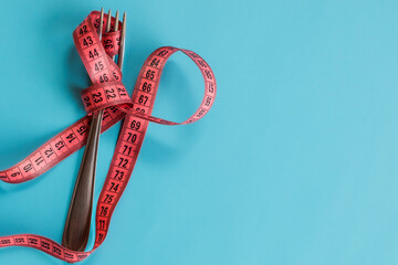 Garfo com fita métrica magenta ao redor, fundo azul dieta
