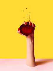 Hand squeezes beets with force and drops fly up over pink yellow background. Contemporary artwork....