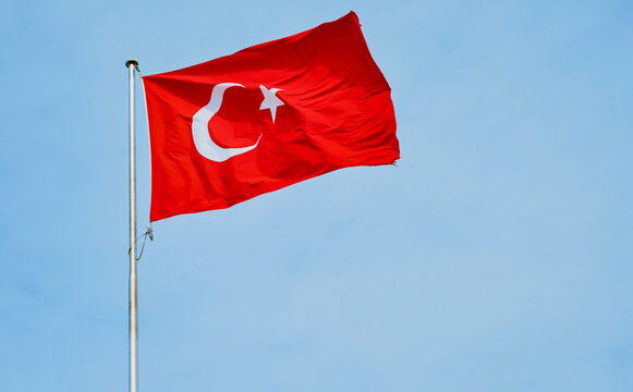 Republic of Turkey flag fluttering in the wind against a blue sky, background with copy space
