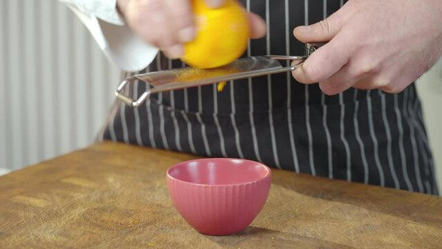 The cook grates the orange peel. Doing Spice From Orange Peel in red bowl Slow motion video