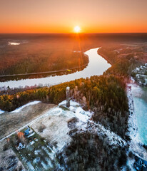 drone picture of sunset, watchtower, forest and river can be seen, snow present