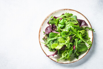 Green salad, fresh leaves in white plate. Top view.