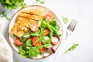 Healthy food plate on white. Green salad with roasted chicken fillet. Top view with copy space.