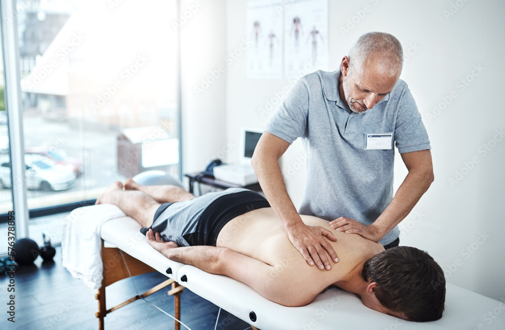 Poster the source of your pain lies in your back. shot of a physiotherapist treating a patient.