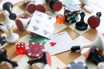 Wooden checkers, chess pieces, playing cards, board games on a light table close up.