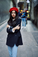 Fashion woman portrait walking tourist in stylish clothes with red lips walking down narrow city street, travel, cinematic color, retro vintage style, dramatic look without smile sadness.