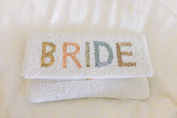 A bride's white clutch with the words "Bride" in colorful letters.