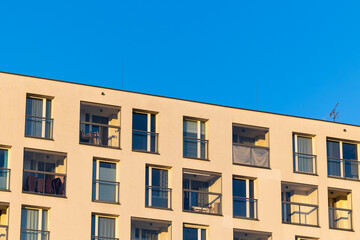 Fototapeta premium Facade with balconies in an apartment block. Multi-family housing, the object against the blue sky.