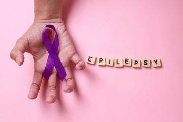 National Epilepsy or Alzheimer disease Day Concept. Purple ribbon symbol on cramped hands with...