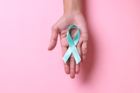 Teal awareness ribbon on hand for Ovarian Cancer month, cervical cancer, Polycystic Ovary Syndrome (PCOS) disease, Post Traumatic Stress Disorder (PTSD), Obsessive Compulsive Disorder (OCD)
