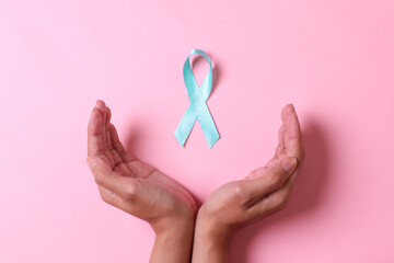 Teal awareness ribbon on hands for Ovarian Cancer month, cervical cancer, Polycystic Ovary Syndrome (PCOS) disease, Post Traumatic Stress Disorder (PTSD), Obsessive Compulsive Disorder (OCD)