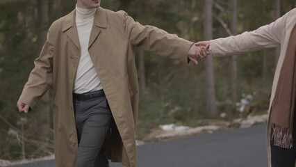 Romantic couple walking along highway in mountains forest. Man takes woman hand and romantic date outdoors. Joyful people boy and girl sit, walk on road. Love couple having fun while walking in nature