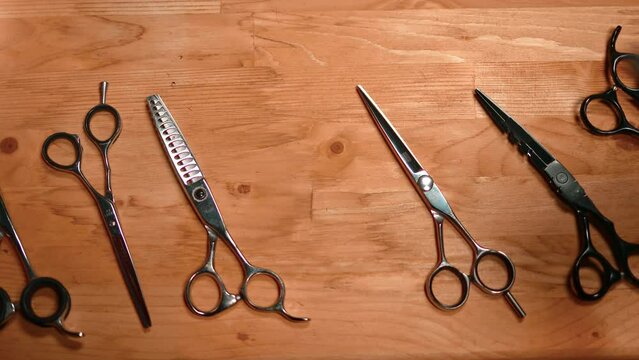 Barber male hand in glove choose hairdressing scissors on wooden table coiffure male salon workshop