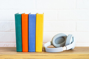 Plakat Headphones and color books at wooden table white background.