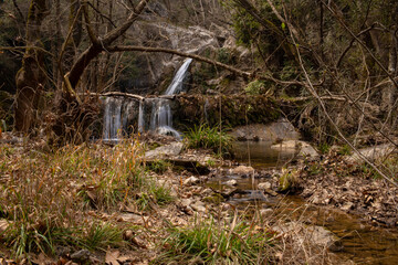 Waterfall in the forest surrounded by trees covered with moss