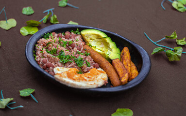 A plate of beans, avocado, sausage and arepa breakfast. Vegan food