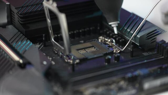 Close-up hands of unrecognizable man wearing gloves blowing dust off slot on motherboard using enema hurricane blower and installing new CPU processor chip after cleaning. Shooting in slow motion.