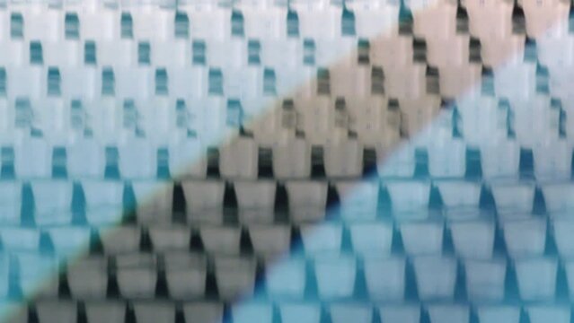 Cubes reflected in blue water in swimming pool with separate tracks before swimming competition on video screen defocused