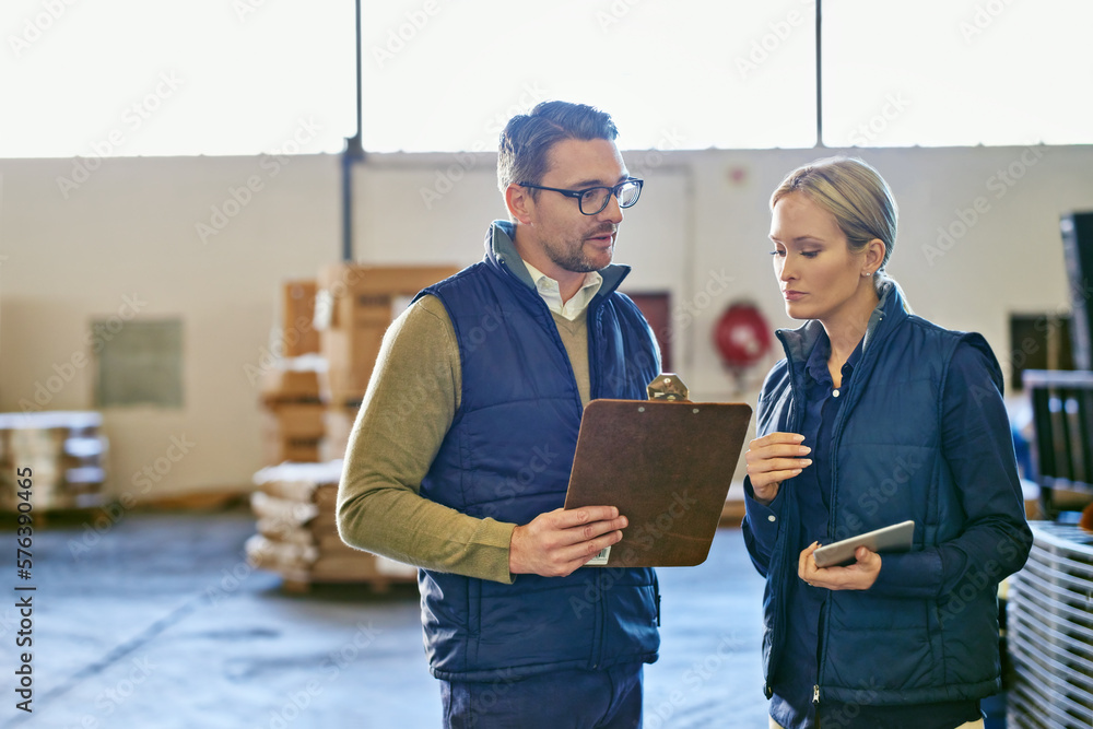 Wall mural these shipments are a priority. shot of two people looking at paperwork while working in a warehouse