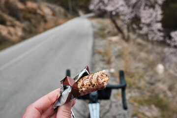 Sports snack for cyclist.A sports bar in the hand of a cyclist against the background of a...