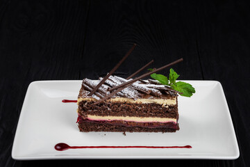 Chocolate cake decorated with mint leaves on black background