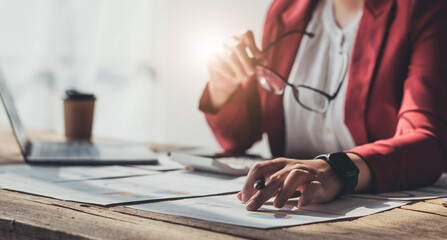 Obraz premium Business woman working in finance and accounting Analyze financial budget with calculator and laptop computer in the office.