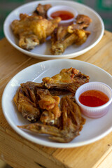 Crispy Fried Chicken with Fish Sauce chicken wings with sauce White Plate wood table focus view