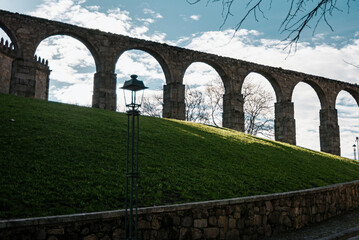 Arches of the Santa Clara Aqueduct in Vila do Conde, Portugal seen from below against the light, with part of the blue sky and clouds