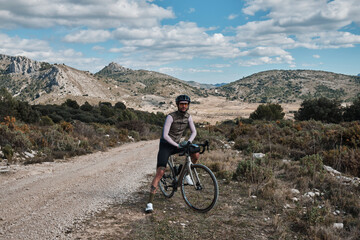 Fototapeta na wymiar Gravel cycling: portrait of a man and his trusty bike.Cyclist is enjoying the serene mountain scenery on his gravel bike.Castell de Castells, Alicante, Spain