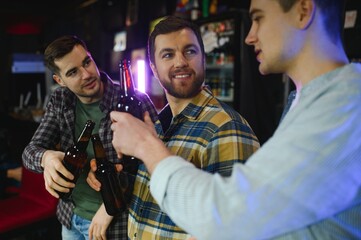 Friends having fun. Happy young men in casual wear drinking beer in pub.