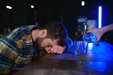 It was a hard day. Depressed young man drinking vodka in bar