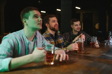 Soccer fans at the bar. Happy football fans cheering at bar and drinking beer while bartender serving beer at the background