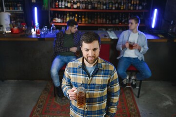 Obraz premium Night in bar. Portrait of cheerful men drinking beer at the bar
