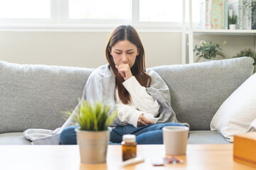 Sick, hurt or pain asian young woman, girl with sore throat, cough have a fever, flu and sneezing nose, runny sitting on sofa bed at home. Health care person on virus seasonal.