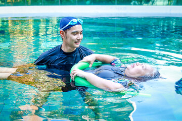Asian man or physiotherapist helping elderly female patient with hydrotherapy It is a rehabilitation and exercise in the water. physical therapy center - obrazy, fototapety, plakaty